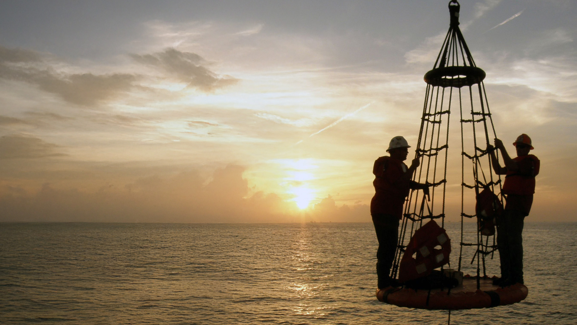 A man wearing a hard hat doing work on an oil rig